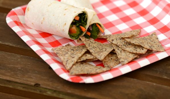 vegan wrap and tortilla chips on red and white checkered plate
