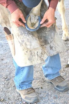 Male farrier working on a horseshoe.