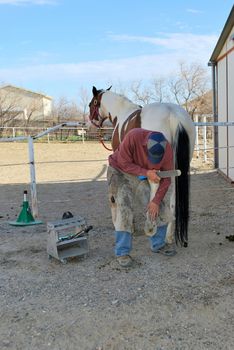 Male farrier working on a horseshoe.