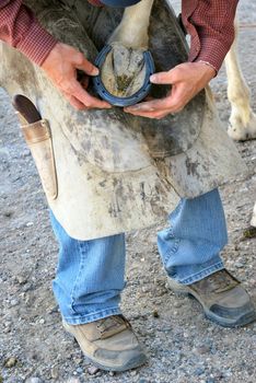 Male farrier working on a horseshoe.