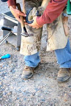 Male farrier working on a horseshoe.