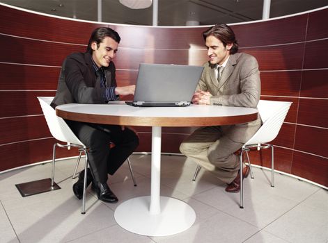Business meeting - two businessmen in suits working together in boardroom
