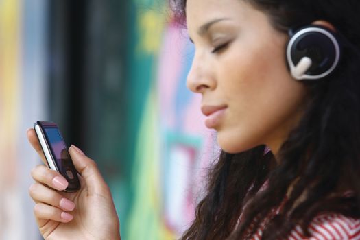 Young beautiful girl listening to MP3 player on the street 