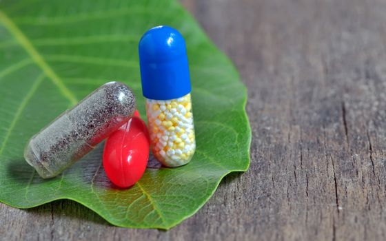 Pills over green leaf nut and old wooden background