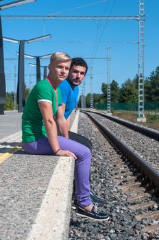 Two young trendy men sitting on the platform