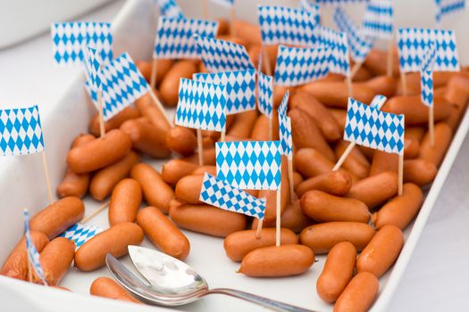 Small sausages with little bavarian flags in a tray on a buffet