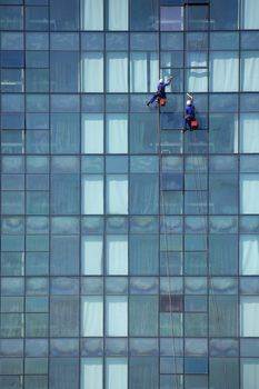 Two window cleaner men high up on the outside of a building