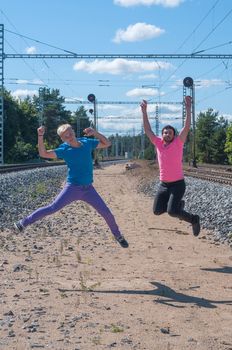 Two handsome young guys jumping near rail track