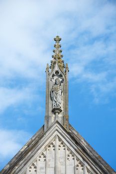 Winchester, UK - June 13, 2014: Stone carving of St. Swithun atop the west facade of Winchester Cathedral, England. The Anglo-Saxon bishop is patron saint of the cathedral.
