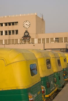 Row of yellow auto rickshaws outside New Delhi railway station in Delhi, India