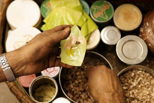 Man making Paan on a street in Old Delhi India. A traditional mix of areca nut and spices wrapped in a betel leave which is chewed and then spat out.