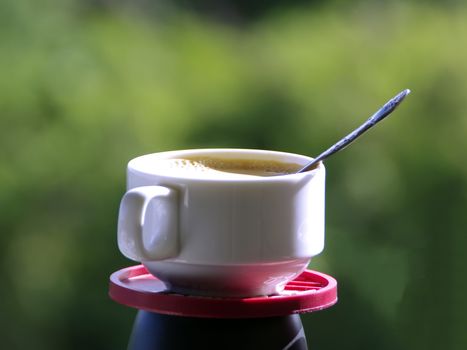 Cap of Coffee on Green Leaves Background.