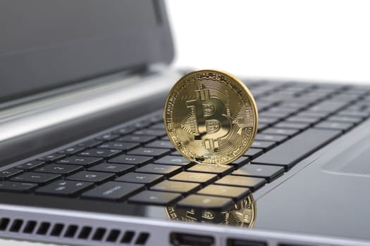 Studio shot of golden Bitcoin virtual currency on laptop. Close-up of front side. 