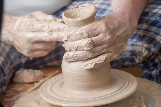 Hands of a potter, creating an earthen jar on the circle