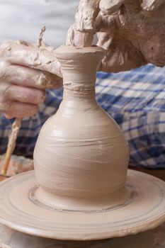 Hands of a potter, creating an earthen jar on the circle