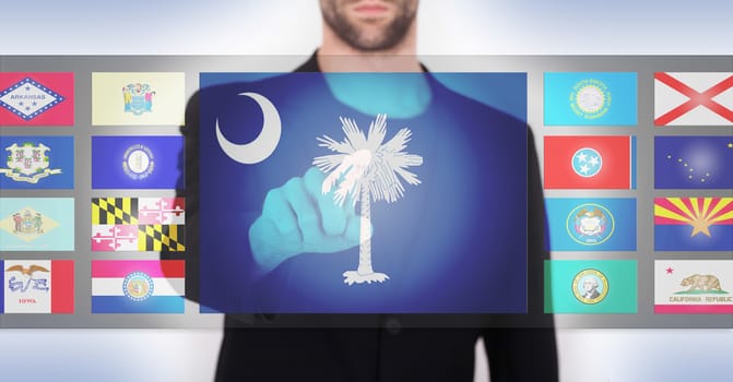 Hand pushing on a touch screen interface, choosing a state, South Carolina