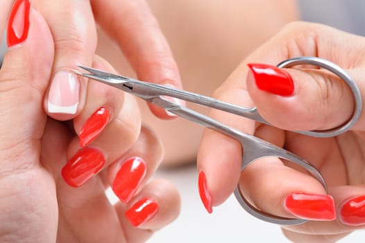 beauty salon, manicure applying, cutting the cuticle with scissors