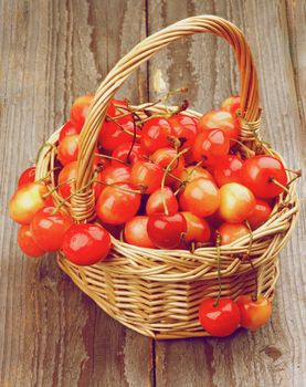 Sweet Maraschino Cherries in Wicker Basket on Wooden background. Retro Styled