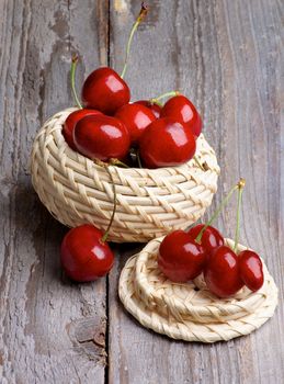 Red Sweet Cherries in Wicker Bowl isolated on Rustic Wooden background