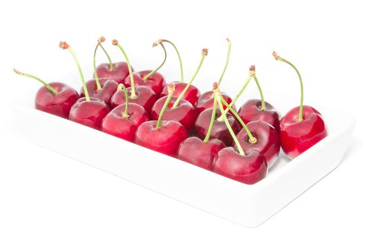 White square dish arranged with big ripe sweet juicy cherry berries tasty fruits isolated on white