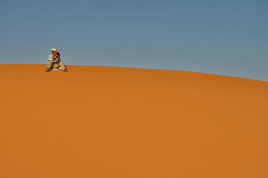 MERZOUGA DESERT - OCTOBER 01: Man in traditional Berber wear taking photograph in Merzouga Desert, Morocco on October 01, 2013.