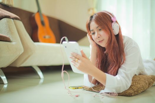 Young asian beautiful woman with smart phone and listening to music at home