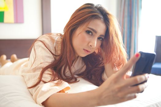 Young asian beautiful woman with smart phone in bedroom at home