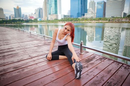 Exercise asian woman stretching hamstring leg muscles in city park