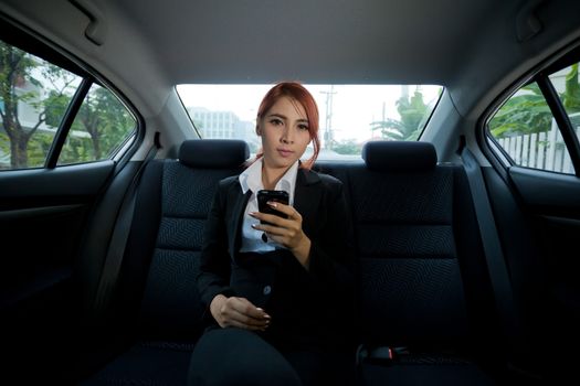 Beautiful young business asian woman using a smart phone in a car