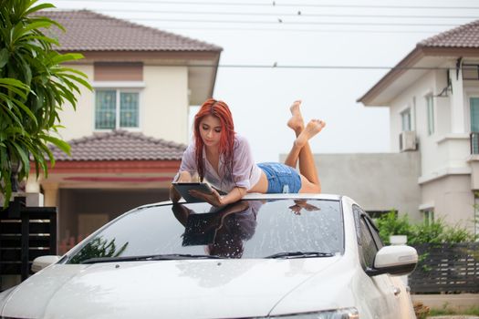 Sexy asian woman washing a car at home