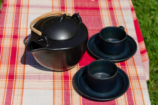 black ceramic tea set on red checked background