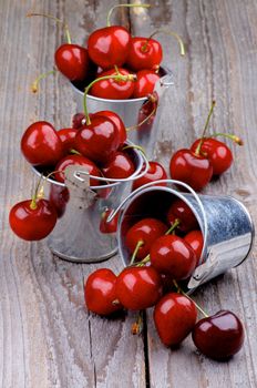 Tin Buckets with Ripe Sweet Cherries isolated on Rustic Wooden background