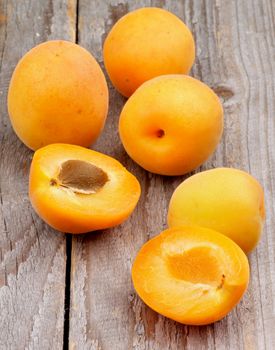 Arrangement of Fresh Juicy Apricots Full Body and Halves isolated on Rustic Wooden background