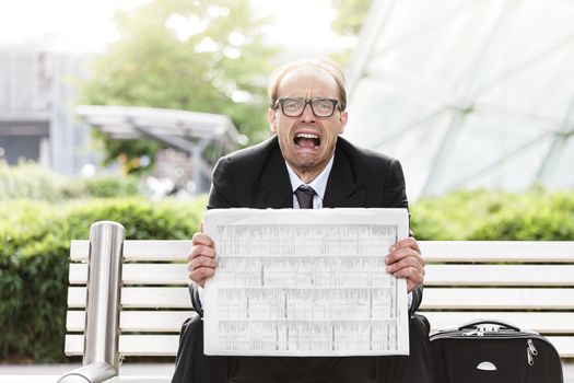 Portrait of screaming businessman with newspaper in his hands 