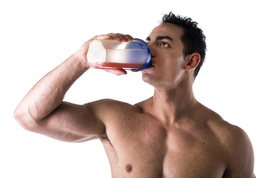 Muscular shirtless male bodybuilder drinking protein shake from blender. Isolated on white, looking up