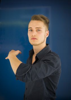 Handsome young man with aggressive expression of challenge, on blue background
