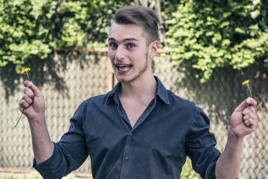 Handsome happy young man with flowers in hands. Outdoors