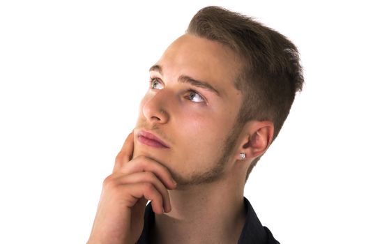 Attractive young man thinking, looking up with hand on his chin, isolated on white background