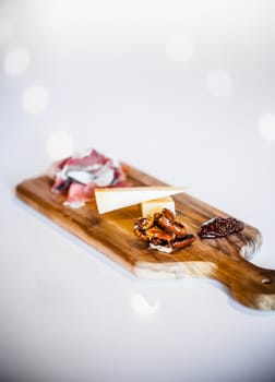 Traditional Portuguese Cheese Platter with Pecans and Prosciutto on a white Counter