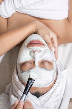 Beautiful young girl with facial mask at beauty salon