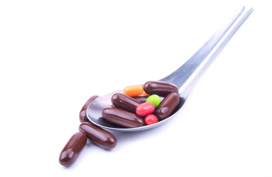 the colorful medicine in the table spoon on the white background