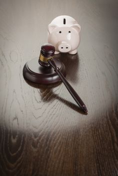 Gavel and Piggy Bank on Reflective Wooden Table.