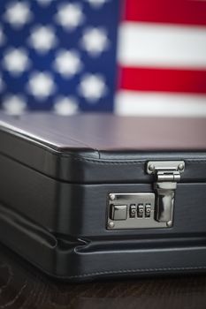 Black Leather Briefcase Resting on Table with American Flag Behind.