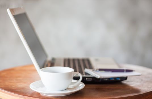 Laptop, notepad and coffee cup on wooden table, stock photo