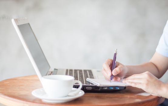 Woman writing on notepad in coffee shop, stock photo