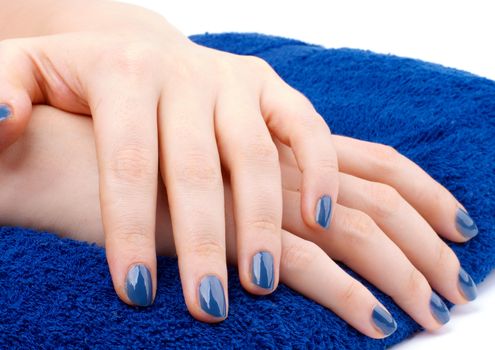 Woman's Hands with Blue Manicure on Dark Blue Towel isolated on white background