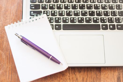 Notepad and laptop on wooden table, stock photo