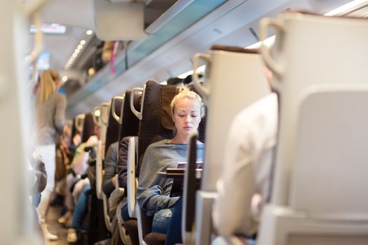 Blonde casual caucasian lady traveling by train. Train full of passengers going to work by public transport at rush hour.