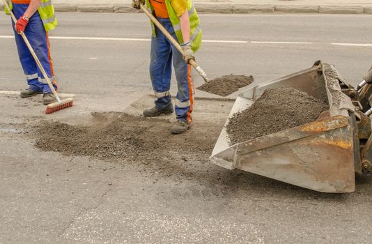worker operating asphalt during road construction and repairing works
