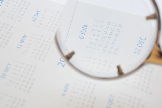 Hand holding magnifying glass to checking calendar of June